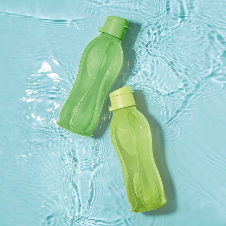Two green reusable water bottles floating on clear blue water