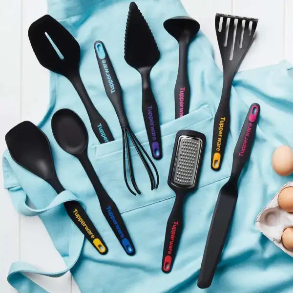 Tupperware keukengerei set met spatels, lepels en rasps op blauwe doek met eieren