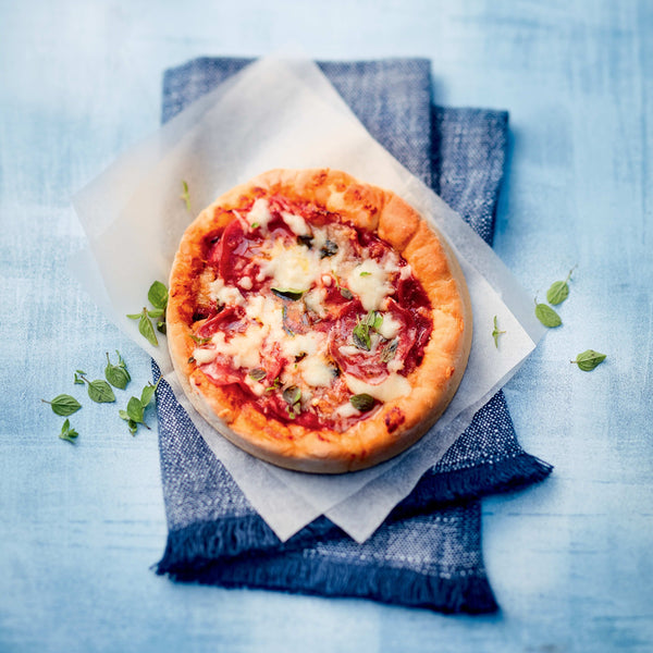 Freshly baked mini pepperoni pizza on parchment paper and a blue napkin.