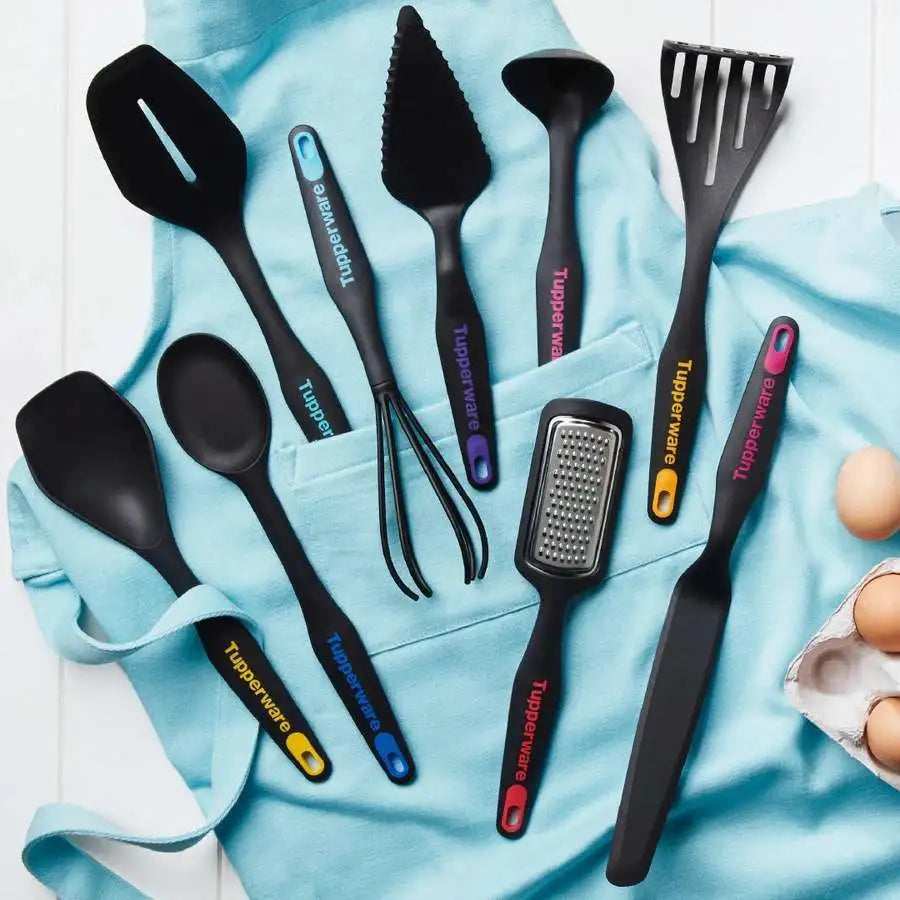 A set of black Tupperware kitchen tools and a cake server on a light blue apron.
