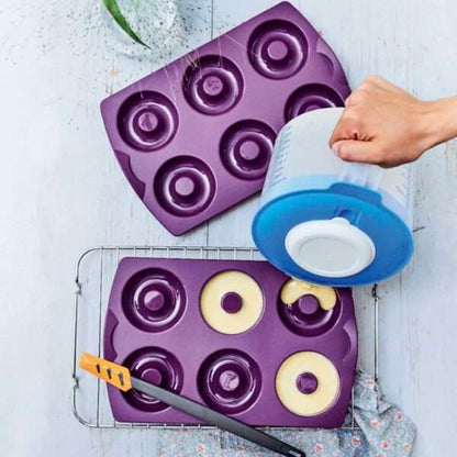 Purple silicone donut baking molds filled with batter on a cooling rack, kitchen utensil visible