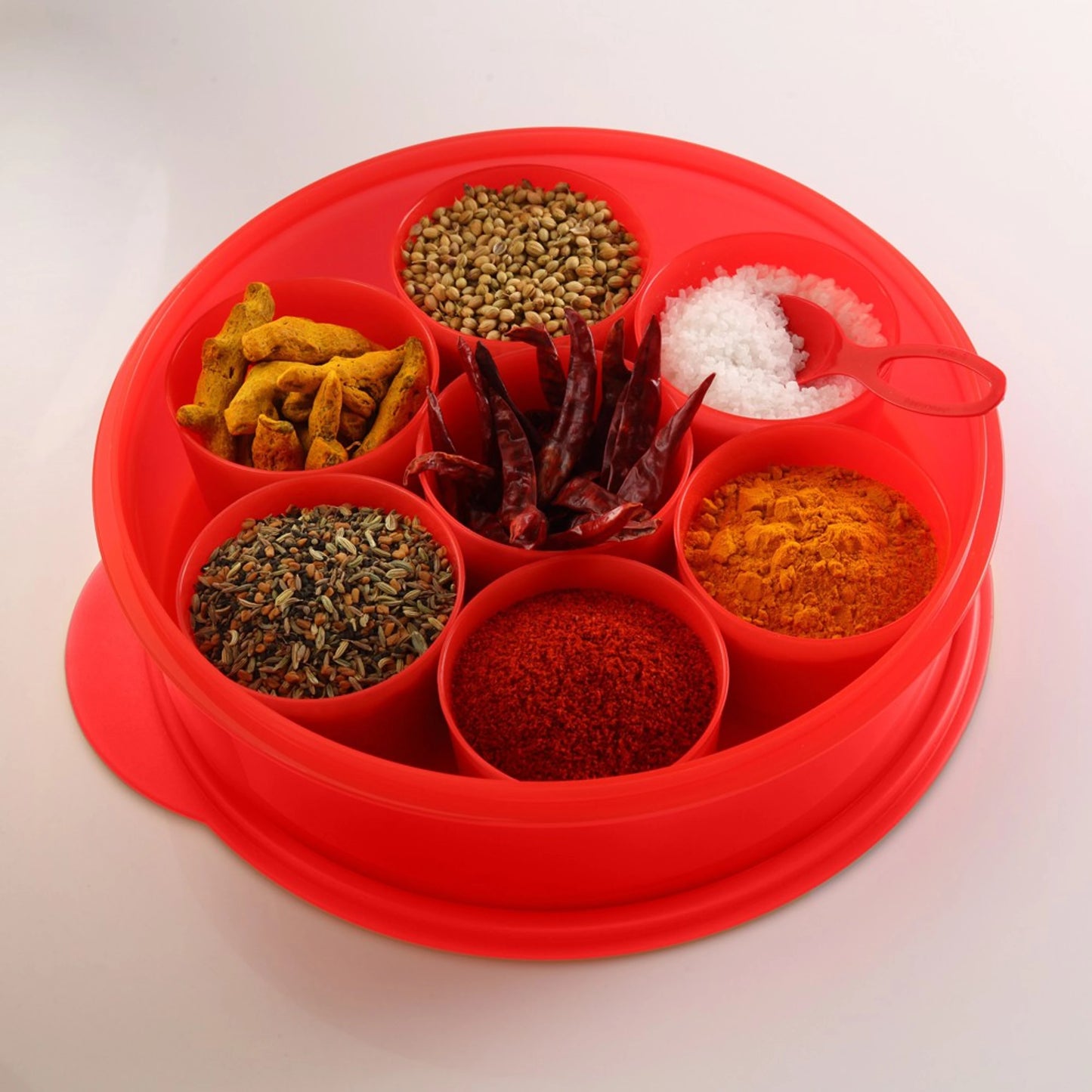 Red plastic spice box with seven compartments filled with assorted spices and salt