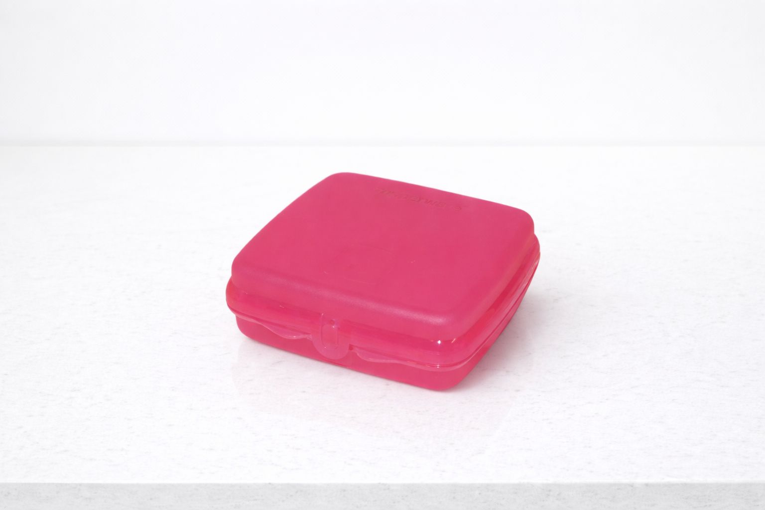 Pink plastic sandwich box on a white countertop for kitchen storage