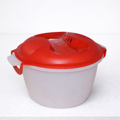 Plastic microwave cooking bowl with red vented lid on white counter
