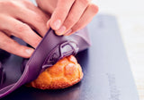 Paarse keukengadget voor het snijden van gebak op een donkere snijplank