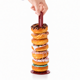 Rode Tupperware pureerstaaf die door een stapel kleurrijke donuts wordt gestoken.
