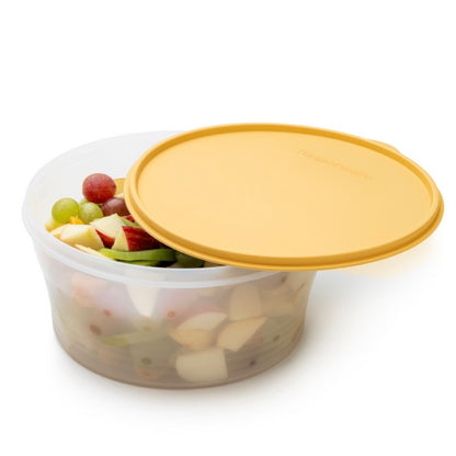 Transparante voedselcontainer met gele deksel, gevuld met fruit zoals druiven en appelstukjes