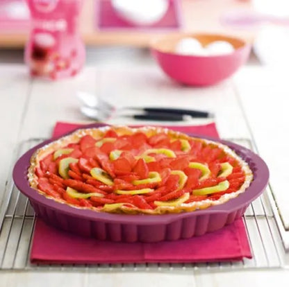 Colorful fruit tart in a purple silicone tart pan on cooling rack in a bright kitchen