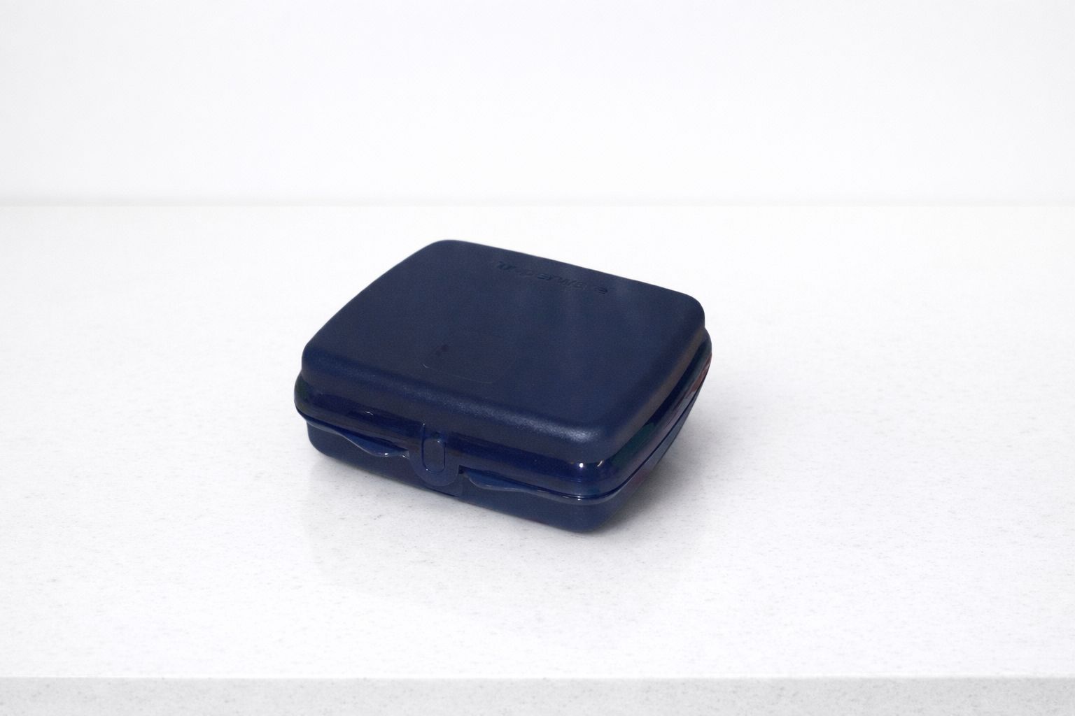 Closed dark blue plastic sandwich box on a white countertop