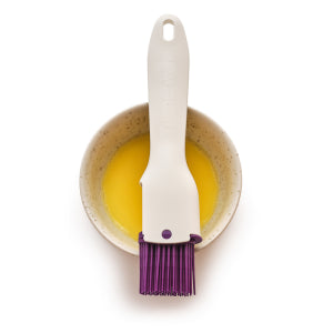 Silicone pastry brush with white handle in bowl of melted butter, kitchen tool flat lay