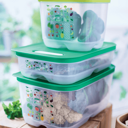 Stack of green-lid plastic food storage containers with fresh vegetables inside