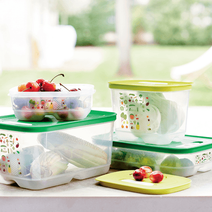 Plastic food storage containers with green lids, storing fresh fruits and vegetables on a kitchen counter