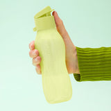 Hand holding a light green reusable plastic water bottle with flip-top lid