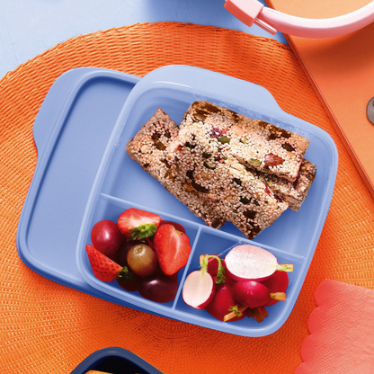 Blue lunchbox with healthy crackers, fresh grapes, strawberries, and radishes on a table