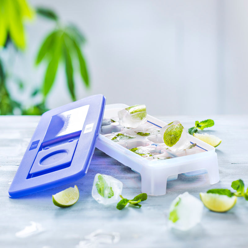 Ice cube tray with blue lid, mint and lime ice cubes on kitchen table