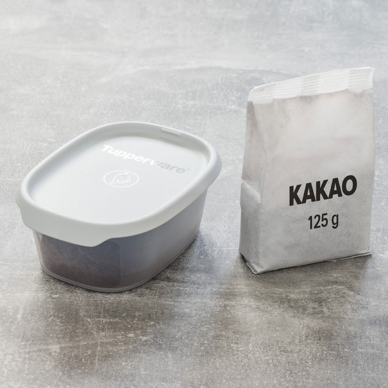 Tupperware opbergdoos met deksel naast zakje kakao, ideaal voor keukenopslag en bakken