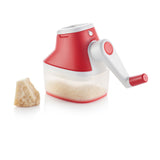 Handheld cheese grater with red handle and container, next to a block of cheese on white background