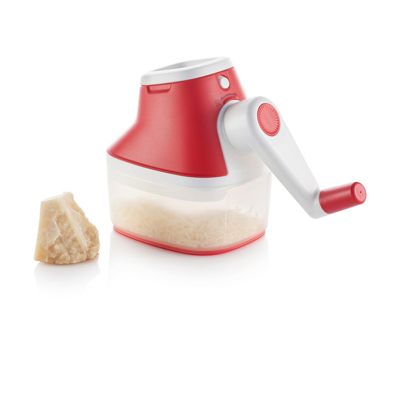 Handheld cheese grater with red handle and container, next to a block of cheese on white background