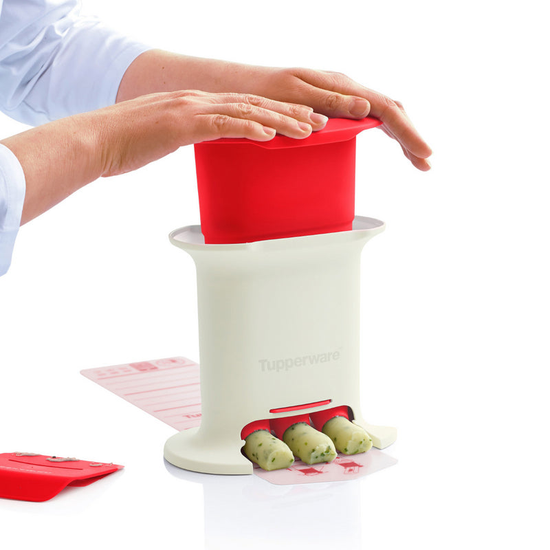 Person using a white and red kitchen tool to shape herb butter sticks on a clean surface
