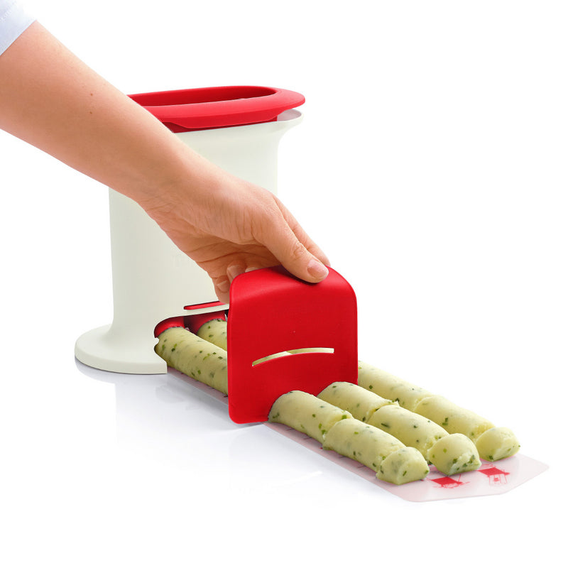 Hand using a kitchen tool with red accents to shape and cut dough rolls on a white surface