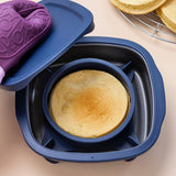 Freshly baked round cake in a blue silicone baking pan with lid and oven mitt