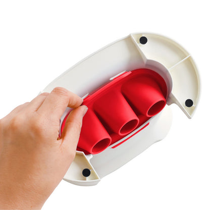 Hand holding a red silicone kitchen tool with four slots and white plastic base