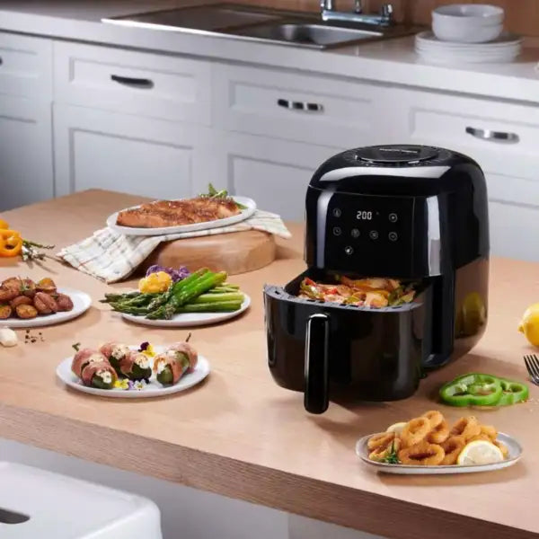 Modern black airfryer with cooked vegetables and snacks on a kitchen countertop
