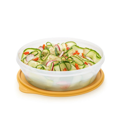 Round plastic food storage container with yellow lid, filled with fresh salad