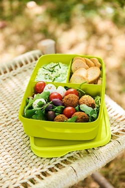 Groene lunchbox met salade, falafel en crackers op rieten tafel, perfect voor gezonde maaltijden onderweg