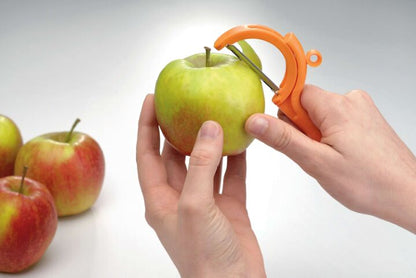 Handen schillen groene appel met oranje schilmes, perfect voor keukentools en culinaire avonturen