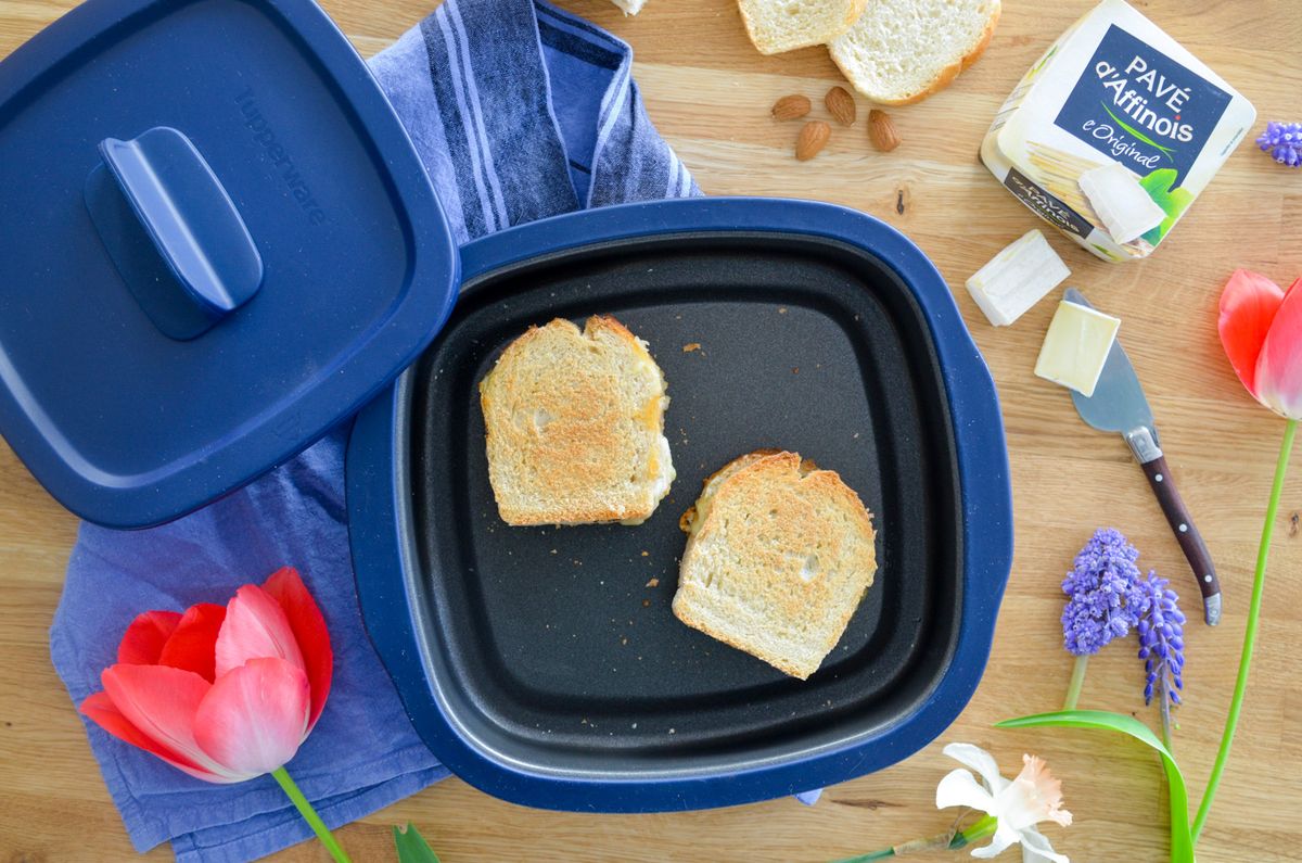 Grilled cheese sandwiches in a blue nonstick baking dish on wooden kitchen surface