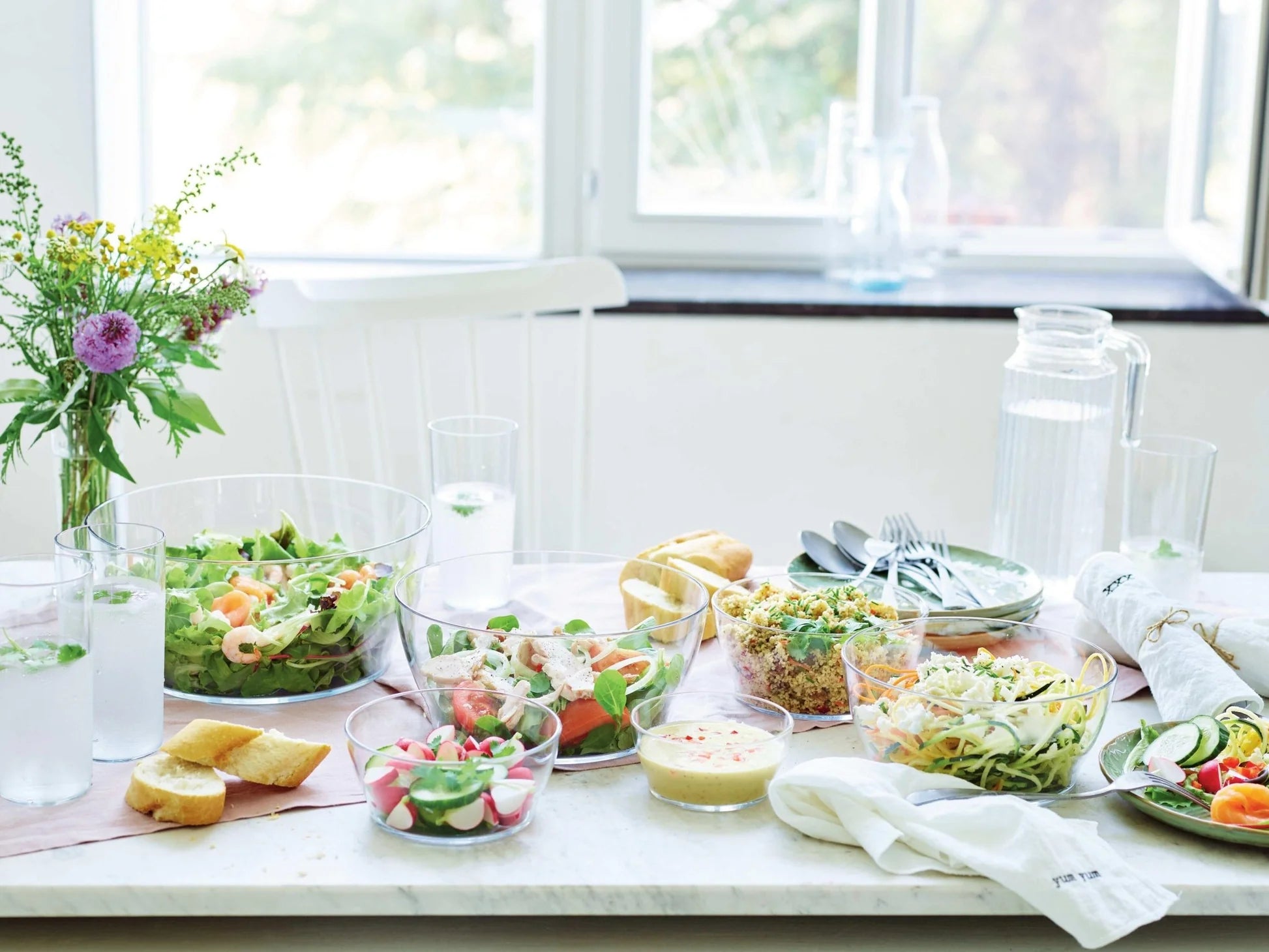 Eco-friendly clear salad bowls with fresh salads on a bright kitchen table setting