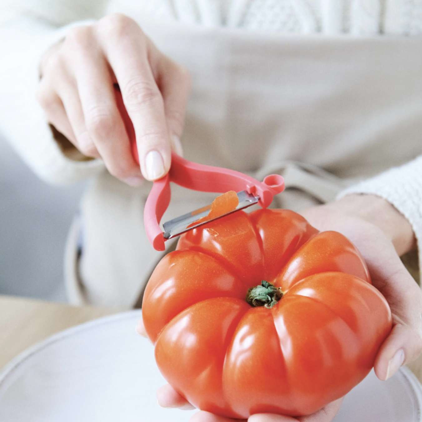 Rood schilmesje gebruikt om een verse tomaat te schillen, perfect voor keukengerei en culinaire gerechten.