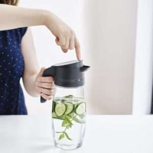 Vrouw gebruikt premium waterkan met komkommer en munt voor frisse drank