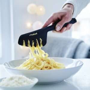 Hand met zwarte pastasporker haalt spaghetti uit witte kom, perfecte keukentool voor pasta lovers