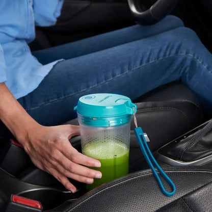Persoon houdt Tupperware smoothiebeker met groene smoothie in auto, ideaal voor onderweg