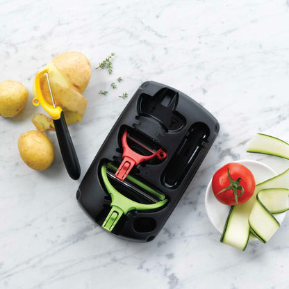 Keukenhulpmiddelen set met schilmesjes en snijgereedschap voor aardappelen en courgette op marmeren achtergrond