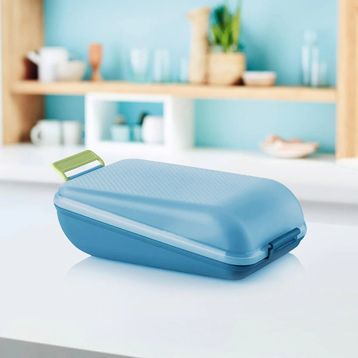 Blue medium lunch box with green handle on kitchen counter, food storage container