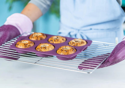 Purple silicone donut baking mold with freshly baked donuts cooling on a metal rack
