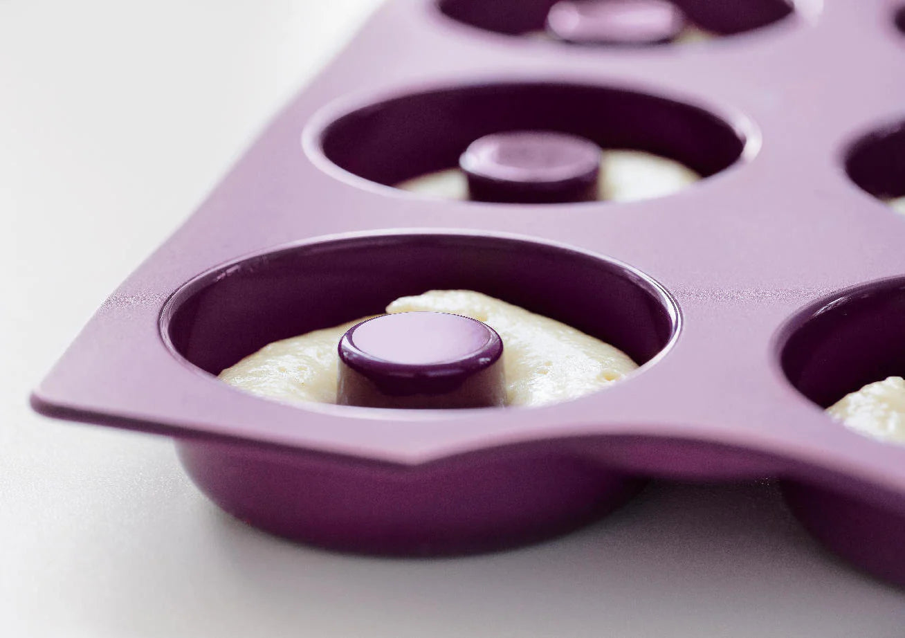 Purple silicone donut baking mold filled with batter, ready for oven use