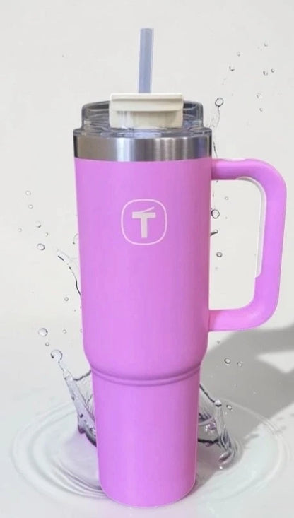 Large pink insulated tumbler with handle, clear lid, and straw, splashing water background