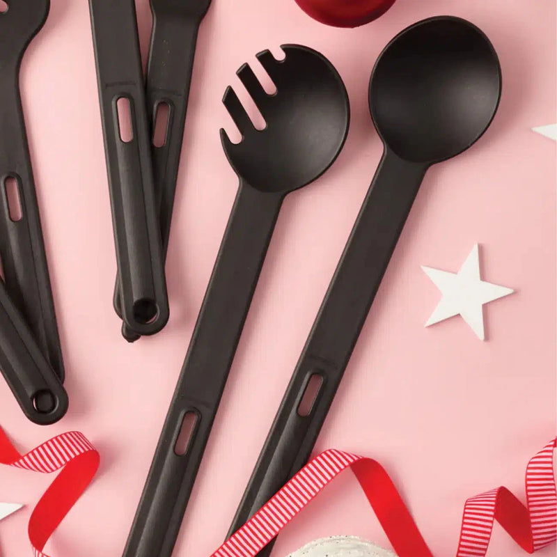 Black kitchen utensils set with spoon and spaghetti server on pink background with stars and ribbon
