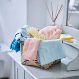Assorted Tupperware Eco glass cloths and cleaning sponges in a woven basket.