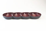 Four-section maroon and black ceramic serving dish on white background