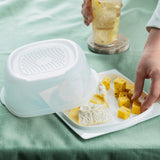 Rectangular cheese storage container with assorted cheeses on a white tray, hand reaching for cheese cubes