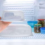 Hand placing butter dish with lid in refrigerator beside jars and containers