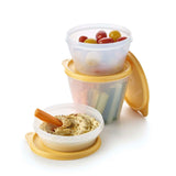 Stack of Tupperware Classico bowls containing grapes, vegetables, and hummus with a carrot.