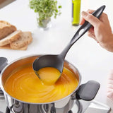 Zwarte soeplepel schenkt oranje soep uit pan, perfect voor culinaire avonturen