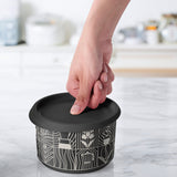 Hand sealing a round food container with a black silicone lid on a kitchen countertop