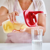 Person pouring water from a Tupperware square fridge jug into a glass.